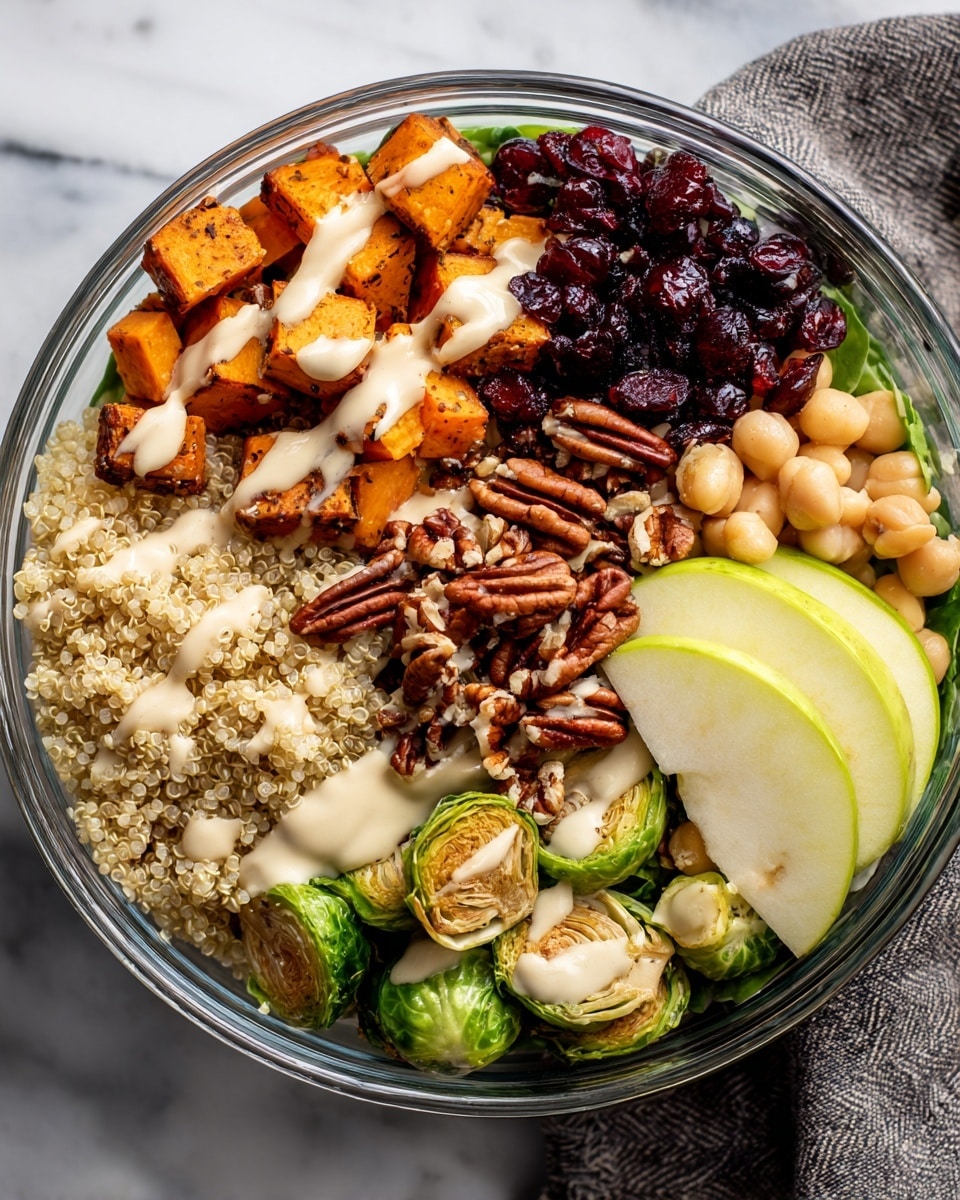 A clear glass bowl holds a colorful layered salad on a white marbled surface. The bottom layer is fresh green spinach leaves. On top, there are roasted golden orange sweet potato cubes and vibrant green Brussels sprouts, halved and slightly charred. Light purple rings of cooked red onion rest near the Brussels sprouts. A generous mound of fluffy, light beige quinoa sits in the center. Scattered throughout are reddish-brown pecans, dried dark red cranberries, and lighter tan walnut pieces. Thin slices of red apple with cream-colored flesh are placed on one side. The salad is sprinkled with small green pumpkin seeds and cracked black pepper, with a light drizzle of dressing visible over some layers. Photo taken with an iphone --ar 4:5 --v 7
