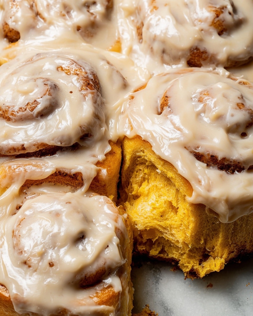 The image shows a close-up of several cinnamon rolls covered with thick, creamy beige icing mixed with tiny dark specks. Each roll has multiple visible layers of soft, golden-brown dough spiraled tightly. The icing generously coats the rolls, pooling in between and around them, creating a smooth, shiny surface. Two rolls are broken open, showing the moist and fluffy yellow inside dough while still covered in the creamy icing. The background is a white marbled texture. photo taken with an iphone --ar 4:5 --v 7