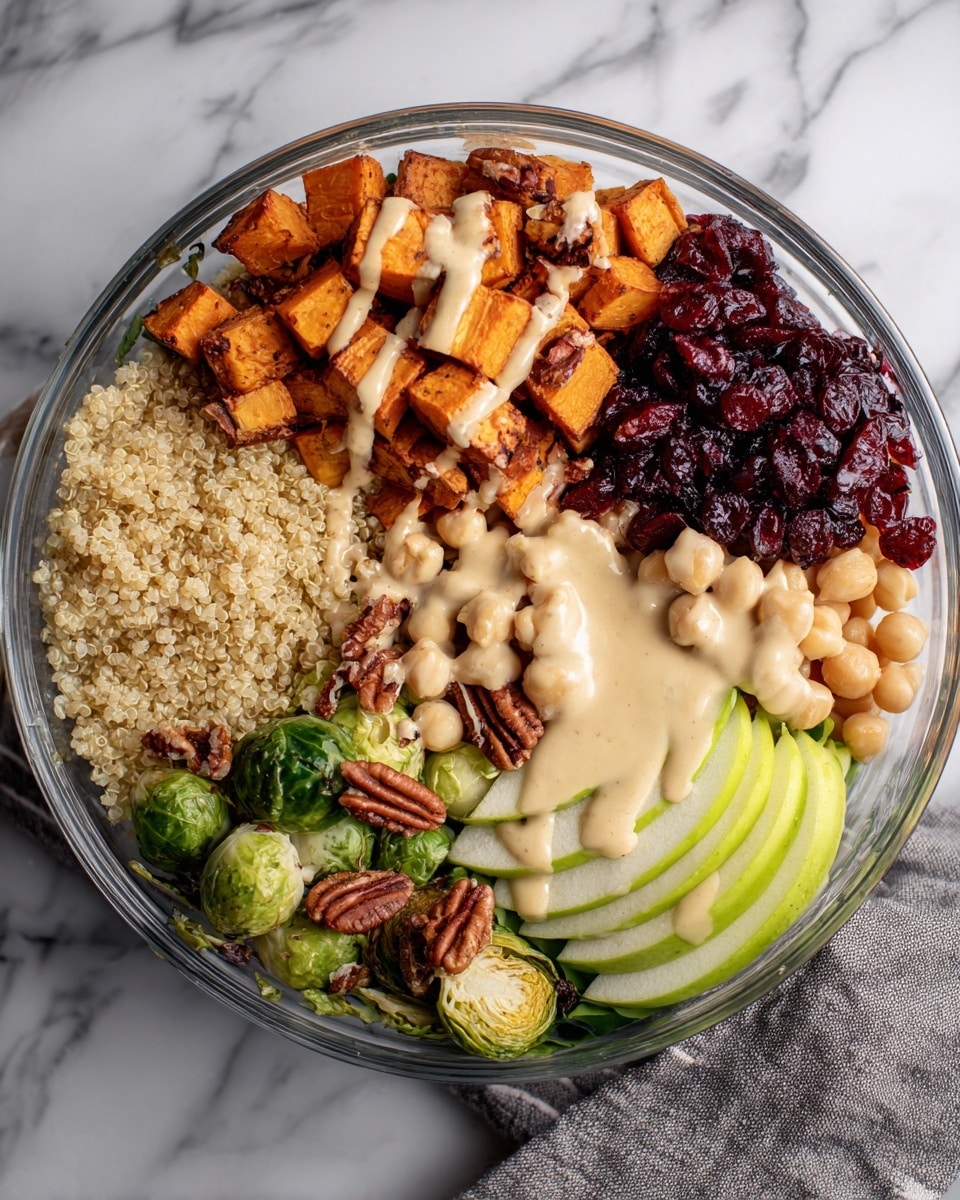 A round glass bowl shows a layered dish starting with a base of green leaves at the bottom, topped with light beige quinoa covering about a third of the bowl on the left side. On top of the quinoa are orange sweet potato cubes sprinkled with pecans and drizzled with a creamy light sauce. Next to the sweet potatoes is a pile of dark red dried cranberries, followed by a cluster of pale beige chickpeas. On the bottom right, there are three pale green apple slices leaning against the chickpeas with a few pecans near them. The bottom section of the bowl also holds roasted green Brussels sprouts with the creamy sauce lightly drizzled over them. The bowl is placed on a white marbled surface with a gray cloth partly visible on the right side. Photo taken with an iphone --ar 4:5 --v 7