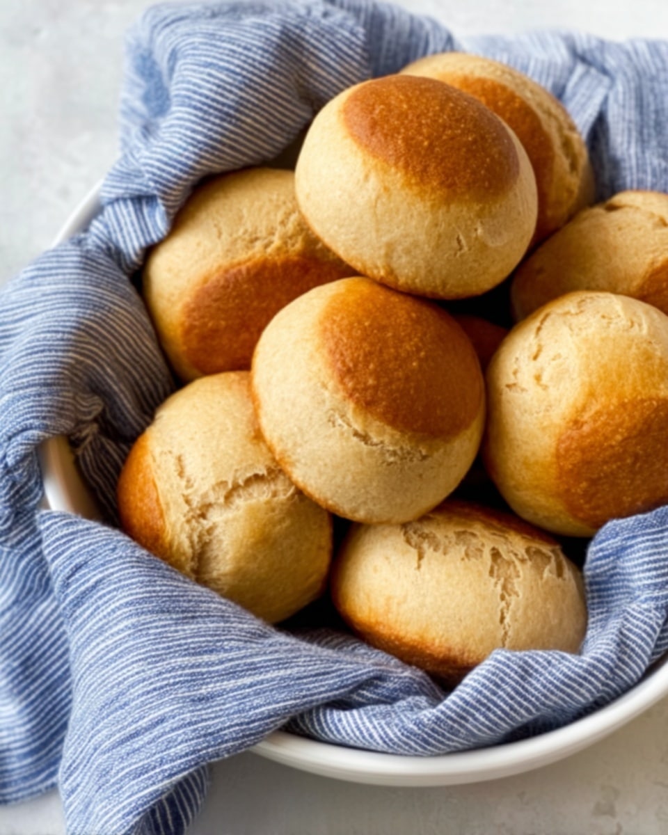 A close-up of a toasted English muffin split in half, placed on a white plate. The bottom half has a golden-brown, slightly crispy surface with a melting, light yellow pat of butter resting on top. Around the butter, there is a thin layer of honey or syrup giving a shiny, sticky texture. Small green bits, likely chopped chives, are scattered lightly over the butter and syrup. The top half of the muffin is toasted to a lighter golden color with a soft, airy texture and also has a few green bits on it. The plate sits on a white marbled surface. photo taken with an iphone --ar 4:5 --v 7