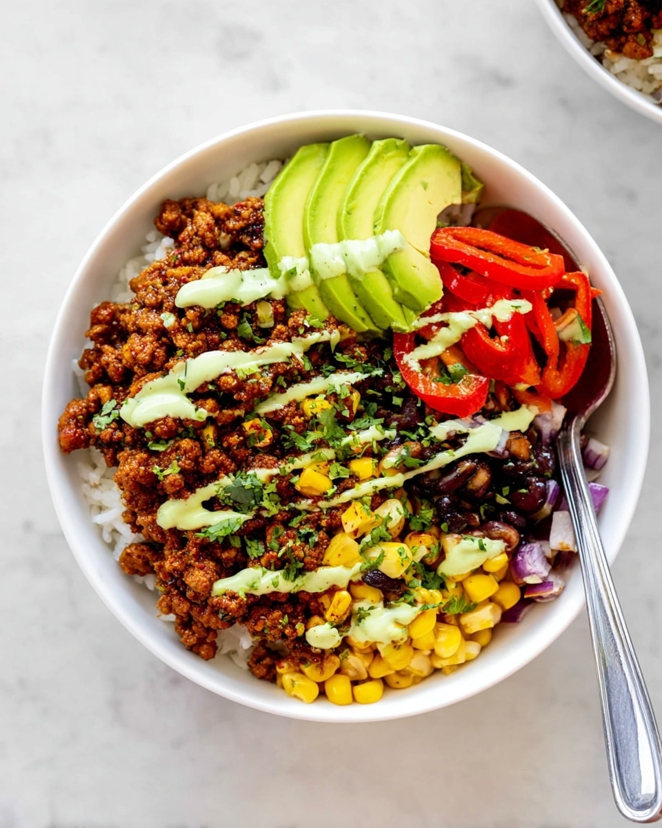 A white bowl filled with a colorful layered dish starting with white rice at the bottom, topped with seasoned crumbled meat that is brown and crumbly, followed by black beans mixed with yellow corn and diced red onion on one side, bright red bell pepper strips beside the meat, and three slices of fresh green avocado on the edge. The whole bowl is drizzled with light green creamy sauce in thin lines, and there is some fresh green cilantro scattered on top. A spoon is placed inside the bowl on the right side against a white marbled surface. photo taken with an iphone --ar 4:5 --v 7