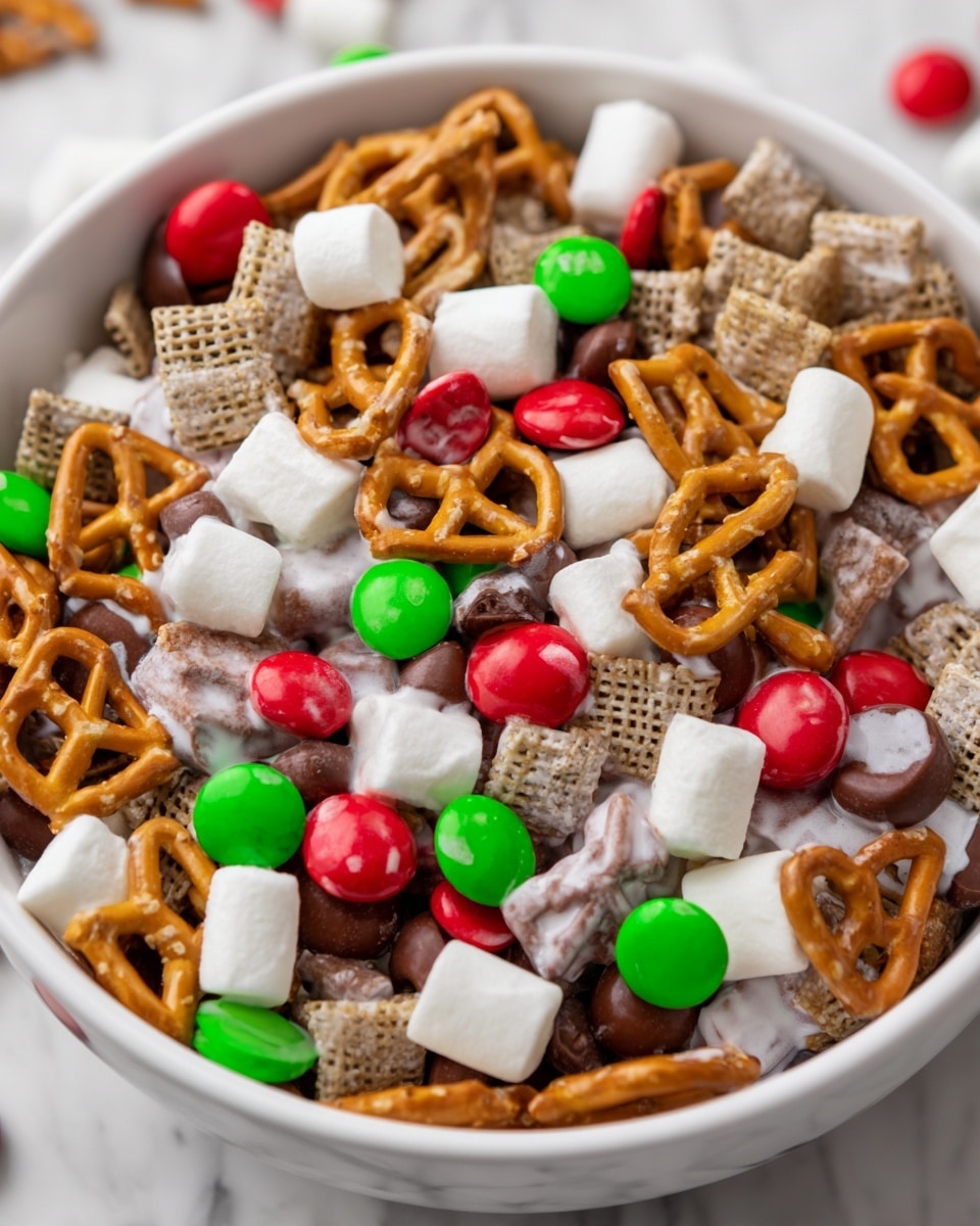 A white bowl filled with a colorful mix of snack items sits on a white marbled surface. The mix includes golden brown pretzel squares scattered evenly throughout, small red and green candy-coated chocolates, miniature white marshmallows, chunks of milk chocolate, and pretzels covered in white yogurt or icing. The textures contrast with crunchy pretzels, smooth chocolate pieces, and soft marshmallows, creating a festive and varied visual. photo taken with an iphone --ar 4:5 --v 7