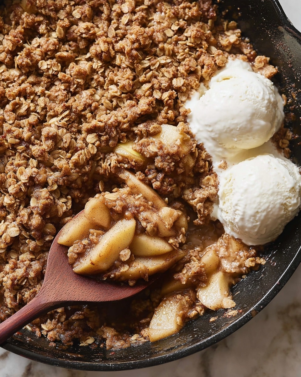A close-up of a baked apple crisp in a black skillet sitting on a white marbled surface, showing a thick, crumbly top layer of golden brown oats and nuts, beneath which soft slices of cooked, cinnamon-spiced apples peek out. On the right side, two scoops of white vanilla ice cream begin to soften, melting slightly into the warm crisp. A wooden spoon rests inside the skillet, lifting a portion of the apple crisp, revealing the juicy apple slices and crumbly topping mixed together. Photo taken with an iphone --ar 4:5 --v 7