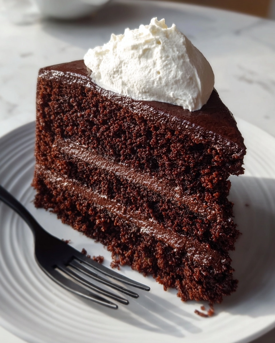 A slice of chocolate cake with two thick layers of dark, rich chocolate sponge separated by a smooth, glossy chocolate filling is placed on a white plate with subtle line patterns. On top of the cake is a dollop of white whipped cream with a soft and airy texture. The cake looks moist and slightly crumbly around the edges. Next to the cake, a black fork rests on the plate. The scene is set against a white marbled surface. photo taken with an iphone --ar 4:5 --v 7