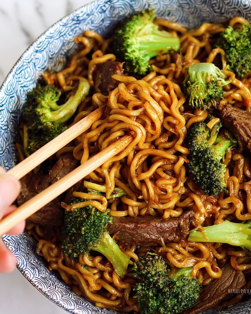 The image shows a close-up of a white bowl filled with stir-fried noodles, pieces of cooked beef, and bright green broccoli florets mixed in. The noodles are golden brown and glossy from the sauce, tangled together in the middle. Several chunks of tender, dark brown beef are scattered throughout, with visible grill marks and a slight sear. The broccoli adds a fresh, vibrant green contrast with its textured, small florets and light stems. A pair of light wooden chopsticks is resting on top of the noodles, lifting a portion of them. The bowl sits on a white marbled surface. photo taken with an iphone --ar 4:5 --v 7