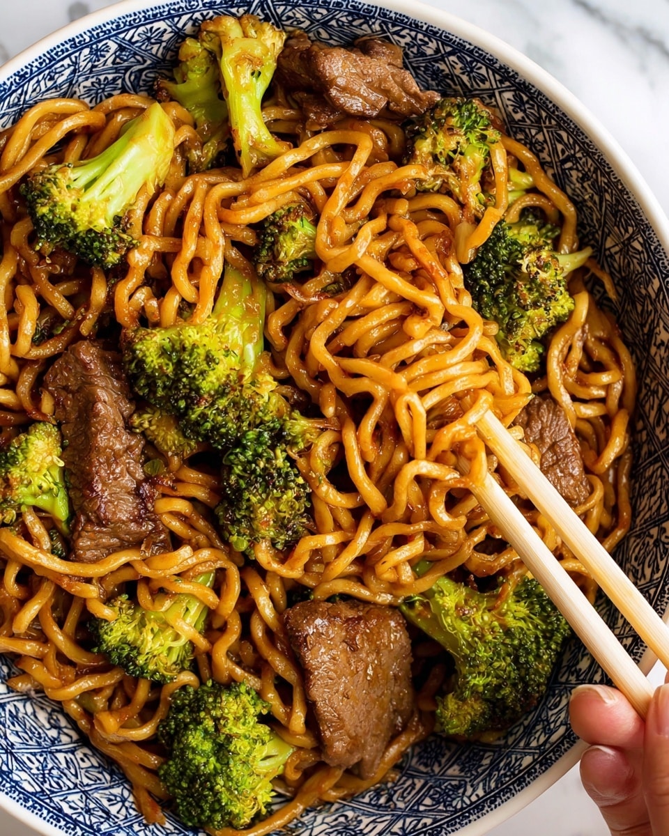 A close-up view of a dish in a white bowl with a blue pattern, showing thick curly noodles coated in a glossy brown sauce as the main layer, mixed evenly with bright green broccoli florets that have a slightly textured surface. Interspersed among the noodles and broccoli are dark brown slices of cooked beef with a slightly charred look. A pair of light-colored wooden chopsticks rest on top of the noodles, picking up some strands, with a woman’s hand holding them from the side. The bowl is set against a white marbled background. photo taken with an iphone --ar 4:5 --v 7