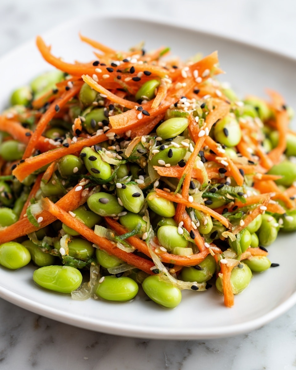 A close-up view of a white square plate filled with a colorful mixed salad showing three main layers: bright green edamame beans form the base, thin sliced carrots in thin orange strips are scattered on top, and there are small green vegetable slices mixed throughout. Tiny black and white sesame seeds are sprinkled evenly over the whole dish, adding a textured look. The plate sits on a white marbled surface. photo taken with an iphone --ar 4:5 --v 7