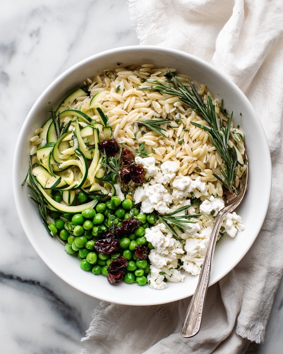 A white bowl with a brown rim holds a mixed dish with three main layers. The base layer is light yellow or pale orzo pasta scattered throughout. On top are bright green peas and chopped zucchini pieces that add a fresh, crisp texture. There are small dark dried berries or raisins mixed in for contrast, and dollops of soft white cheese are spread across the dish in uneven blobs. Sprigs of green herbs like rosemary or dill are sprinkled throughout the dish, adding thin, needle-like shapes. A silver fork rests on the right side of the bowl, partially submerged in the food. The bowl sits on a white marbled surface with a white cloth towel nearby. photo taken with an iphone --ar 4:5 --v 7
